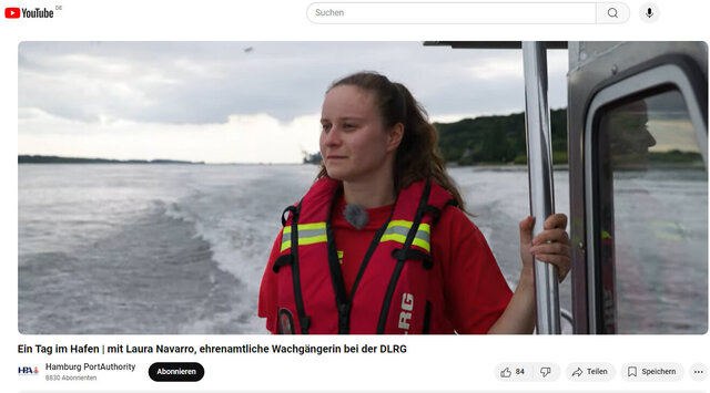 Laura Navarro vom DLRG steht mit Rettungsweste an Bord eines schnell fahrenden Schiffes und guckt auf die Elbe