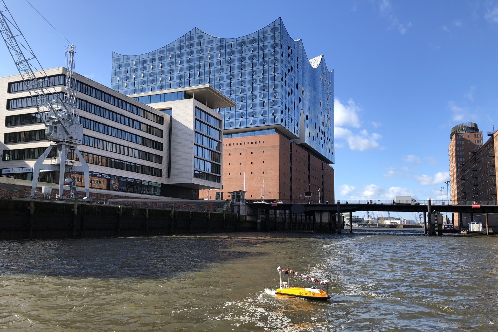 Die gelbe peildrohne Echo.1 mit antennen und einer kamera im hafenbecken in der hafencity in hamburg mit elbphilharmonie im hintergrund