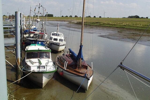 Segelschiffe und Sportboote liegen auf dem Schlick bei Niedrigwasser in einem Nebenfluss der Elbe
