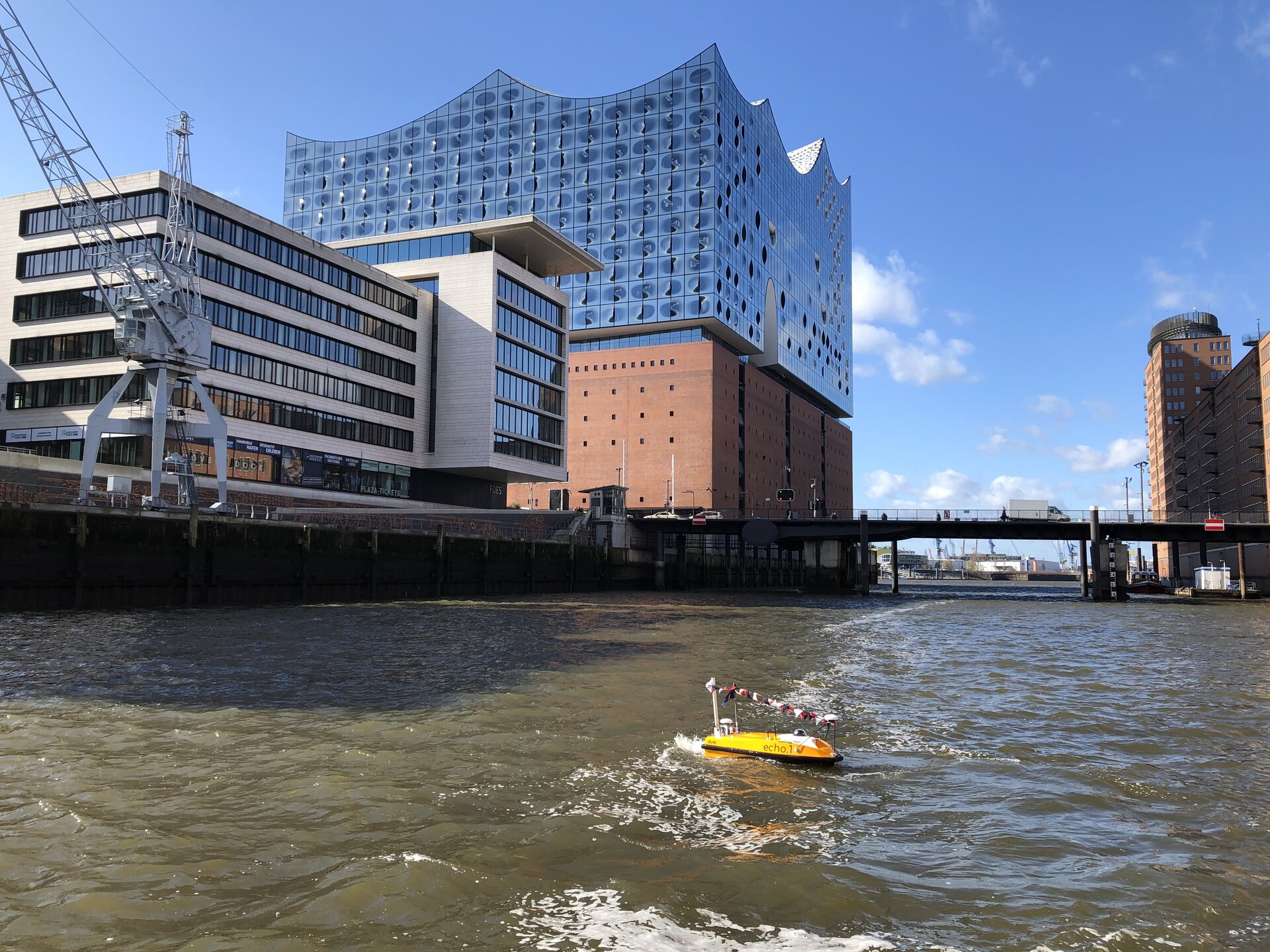 Die gelbe peildrohne Echo.1 mit antennen und einer kamera im hafenbecken in der hafencity in hamburg mit elbphilharmonie im hintergrund